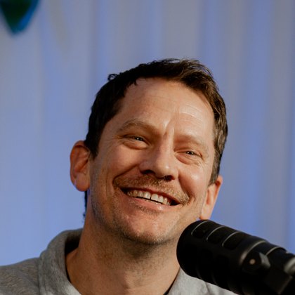 Stu Moerman, smiling, photographed at the studio microphone.